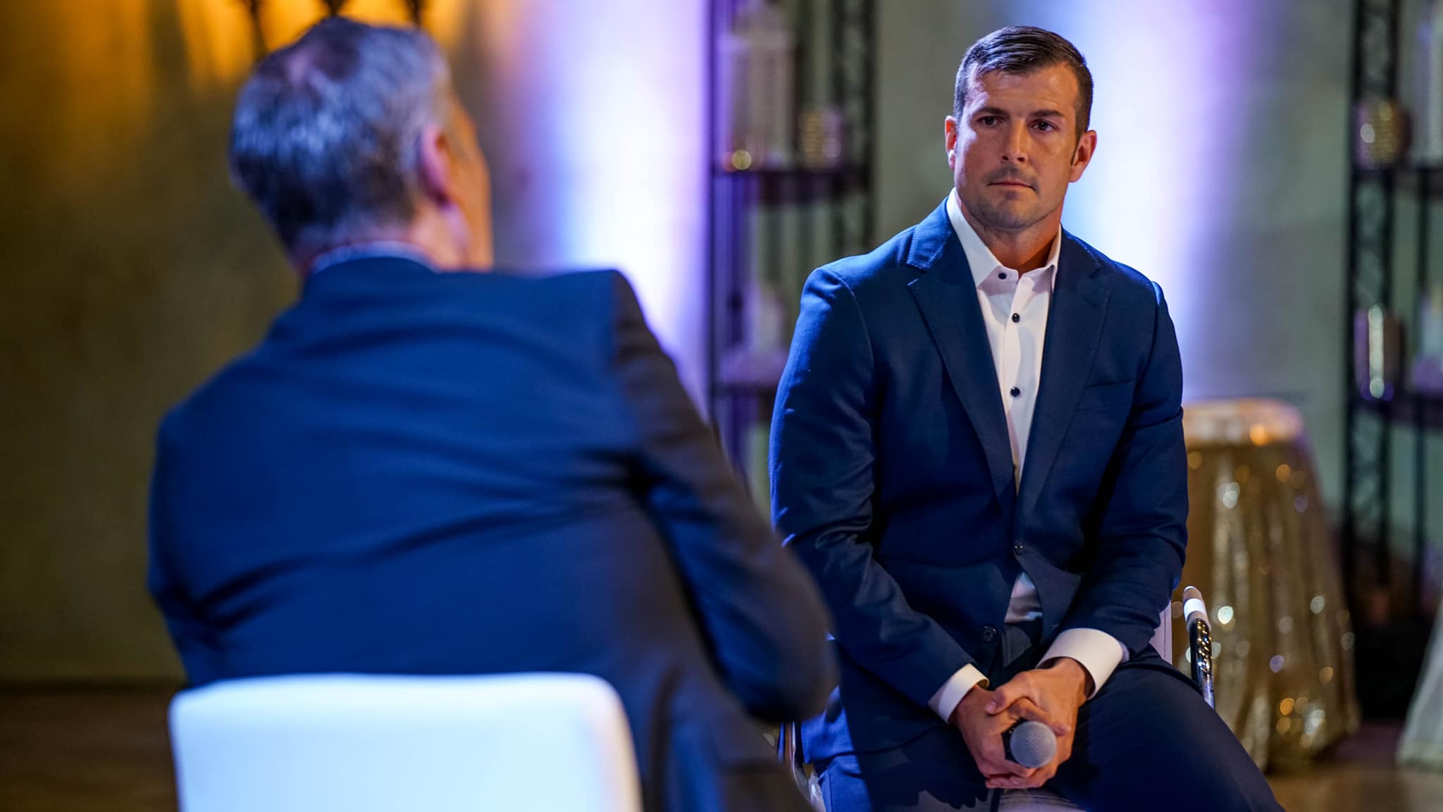 A man in a suit and tie sitting next to another man.